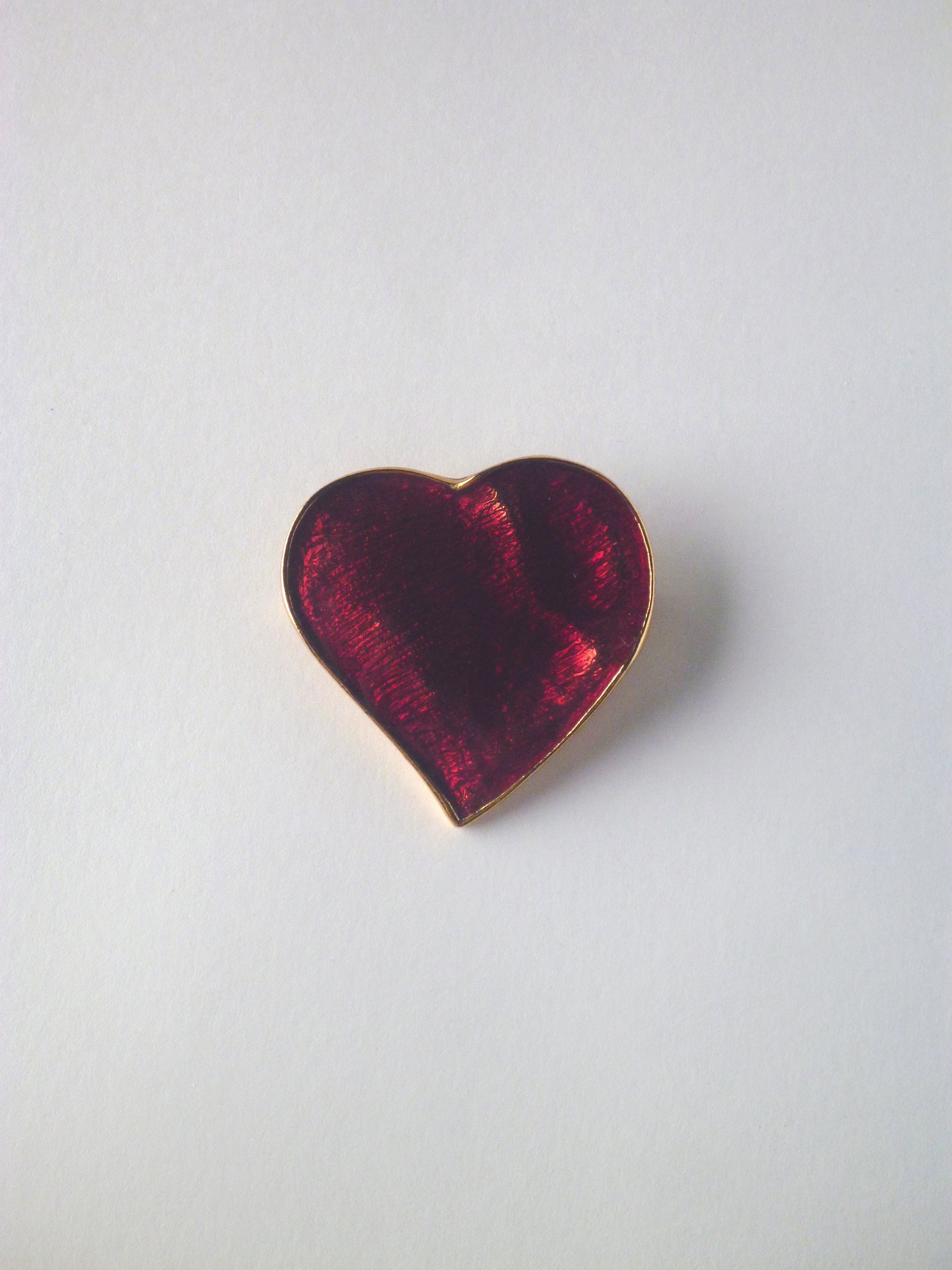 Vintage Yves Saint Laurent heart brooch featuring deep ruby-red enamel with a gold-tone trim.