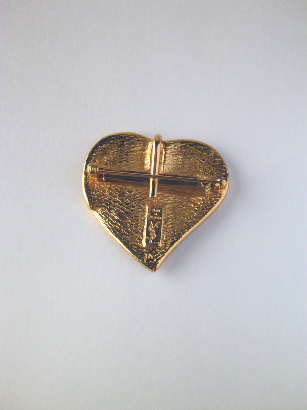 Vintage Yves Saint Laurent heart brooch featuring deep ruby-red enamel with a gold-tone trim.